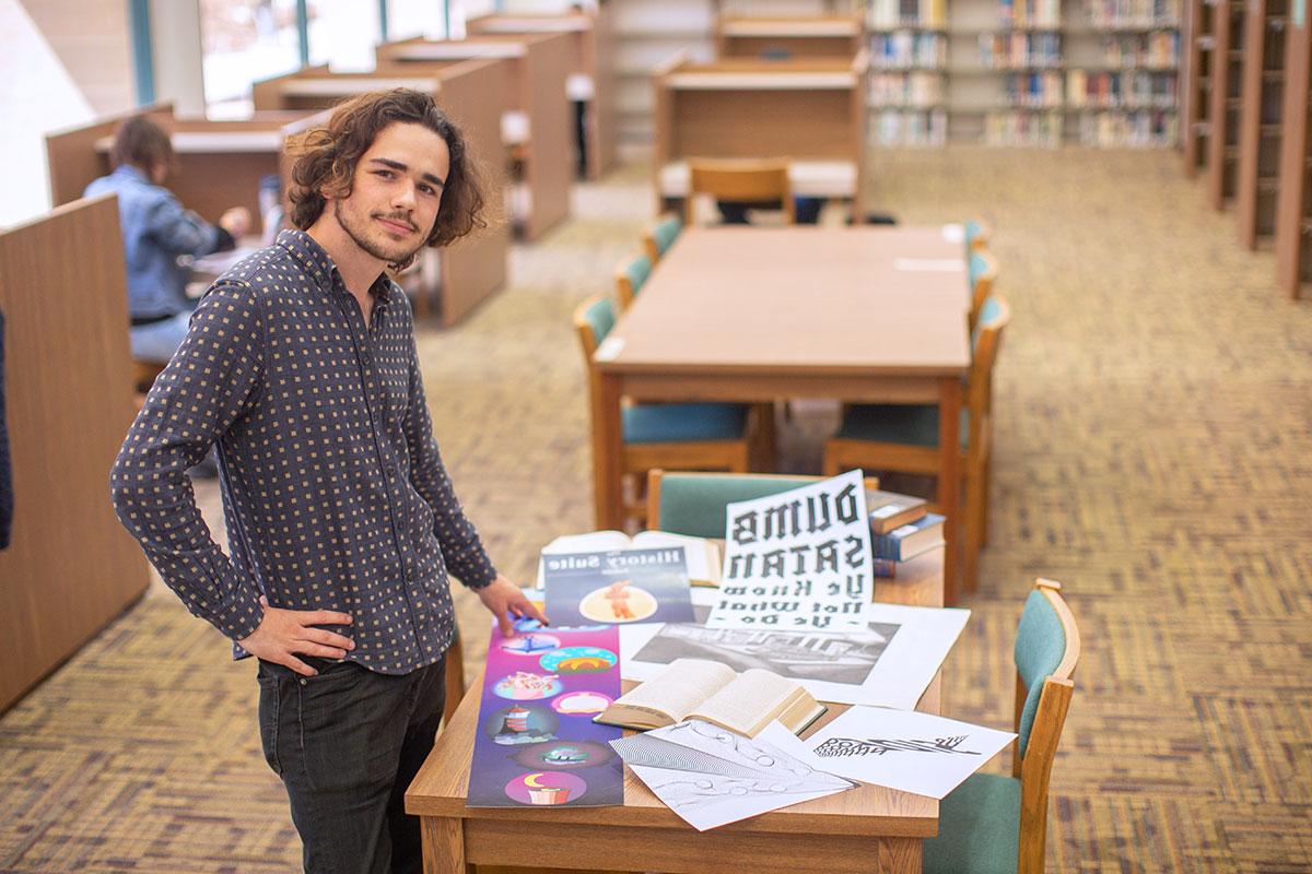 Augustine Mallinson standing next to a table with a variety of projects displayed