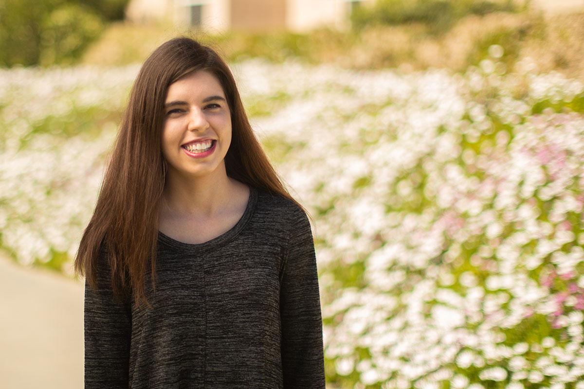 Emily McCarthy standing in front of bed of flowers