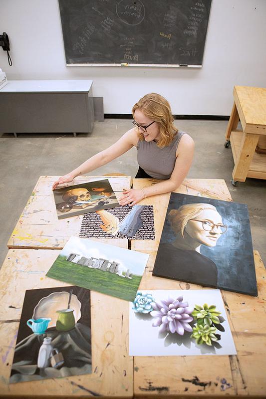 Sami Newport looking at a table covered with an assortment of her projects